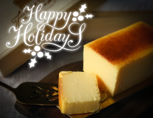 Dark cozy environment with cut Ricotta Cheesecake with Happy Holidays caption