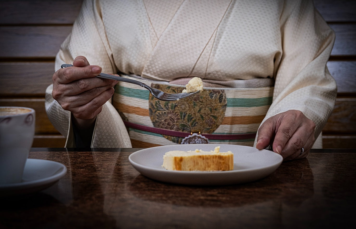 Woman in kimono picking up the Ricotta cheesecake using a fork